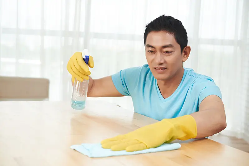 asian-man-rubber-gloves-spraying-table-cleaning-with-cloth-home