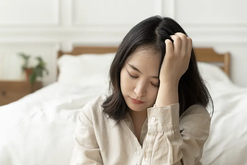 asian-woman-sitting-sad-by-her-bed